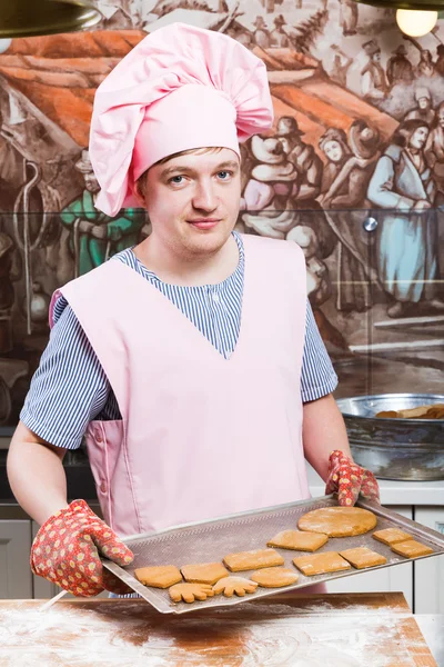 Young male confectioner holding dripping pan