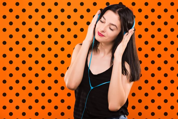 Girl with headphones on orange background