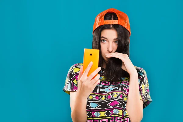 Nice girl, takes selfie on her smart phone, blue background