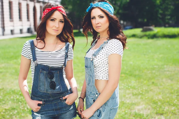 Twins sisters wearing bandanas and overalls