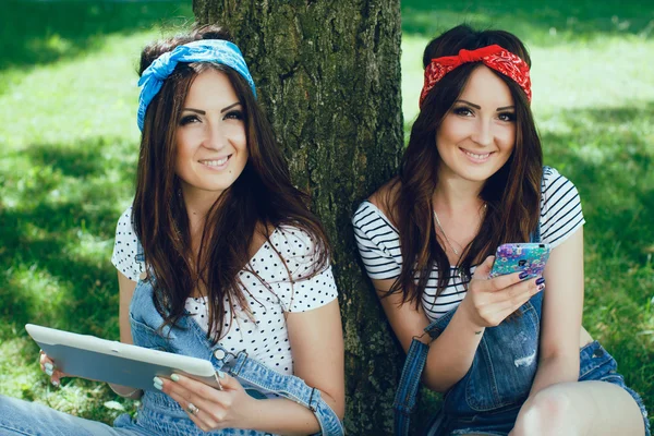 Twins with digital tablet and smart phone