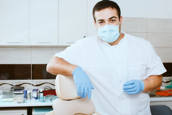 Dentist leaning against dentists chair