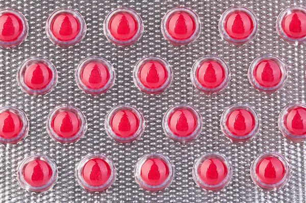 Red pills in blister close-up as a background.