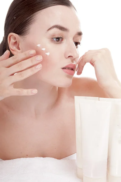 Sensual woman applying cosmetic cream treatment on her face