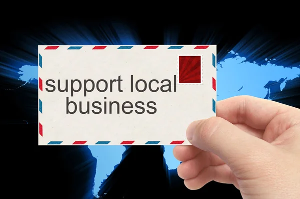 Hand holding envelope with support local business word on world