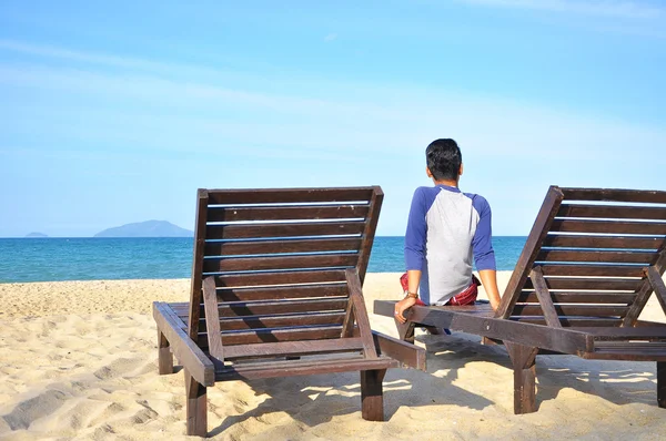 Man sit on beach chair on sand beach. Concept for rest, relaxation, holiday.