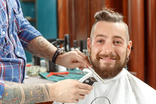 Handsome man getting his beard shaved in a barber shop