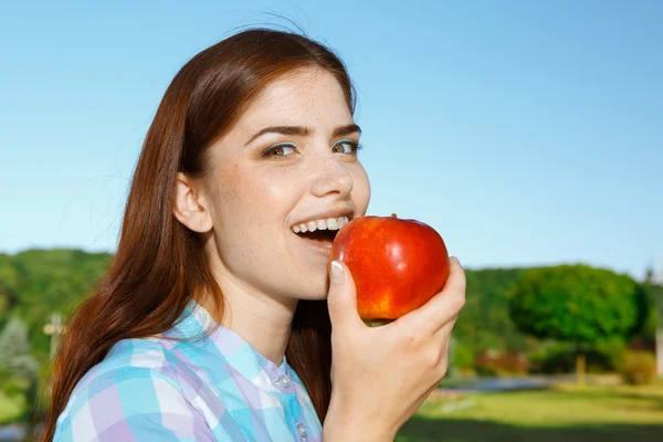 Beautiful girl eating apple in the park
