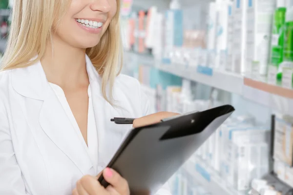 Beautiful pharmacist accounting the product in drugstore