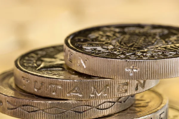 Macro shot of British pound coins precariously balanced.