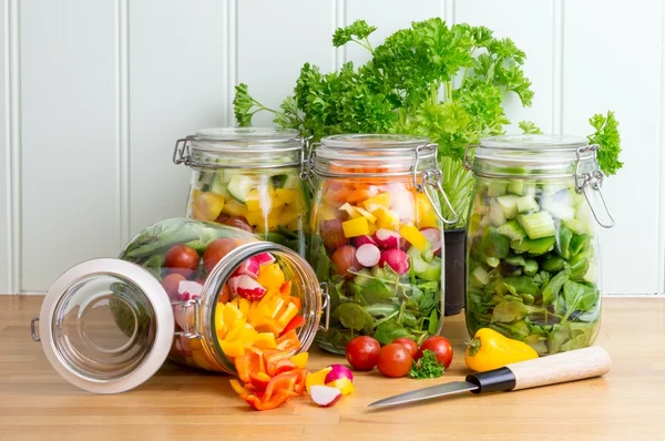 Salad in glass storage jars. One spilling contents.