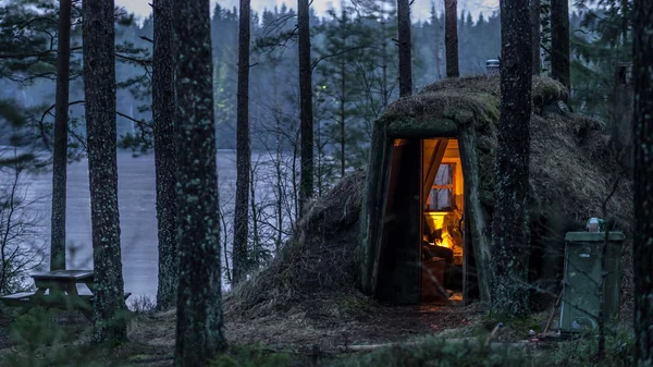 Cozy burrow like shelter in Sweden, the lake behind is iced
