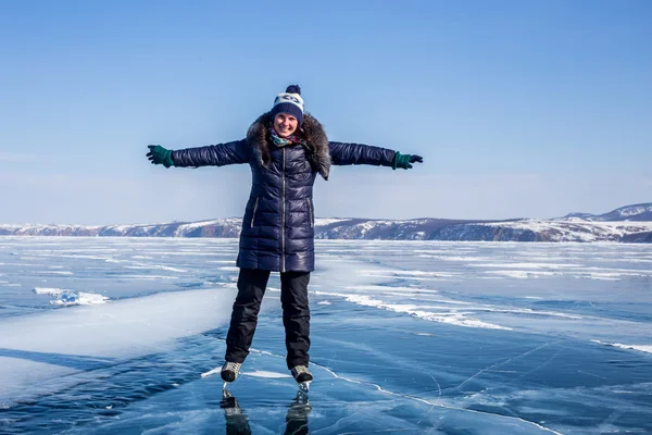 Happy young woman skating on the frozen Lake Baikal