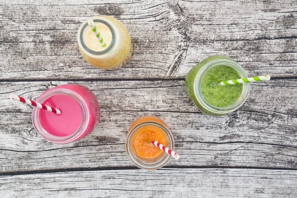 Various colorful fruit smoothies in glass bottles