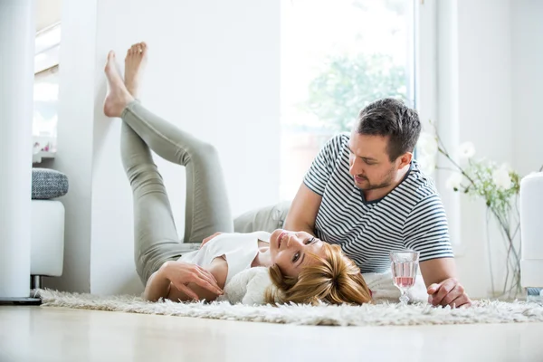 Young couple lying in living room on carpet