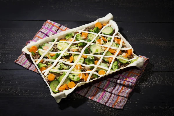 Puff pastry tart with mincemeat, broccoli, carrot and zucchini on baking tray