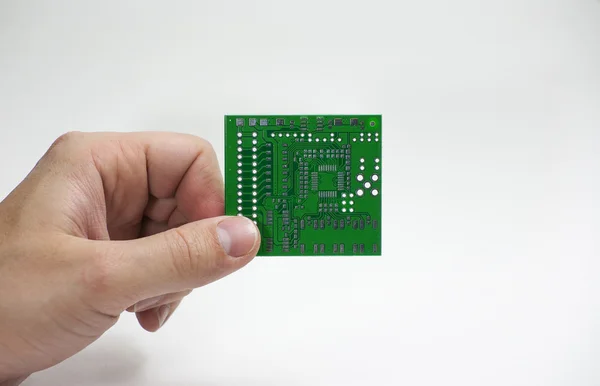 Human hand holding a printed circuit board in fingers