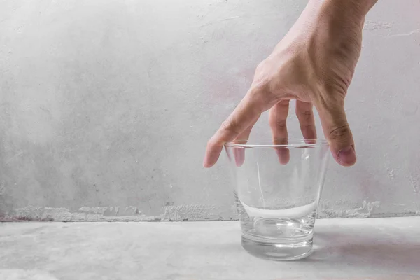 Hand grabbing clear glass of water