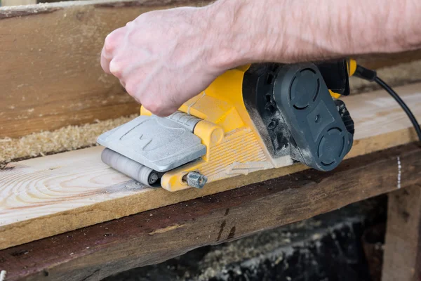 Carpenter works with belt sander in carpentry