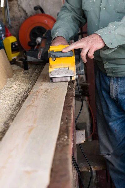 Carpenter works with belt sander in carpentry