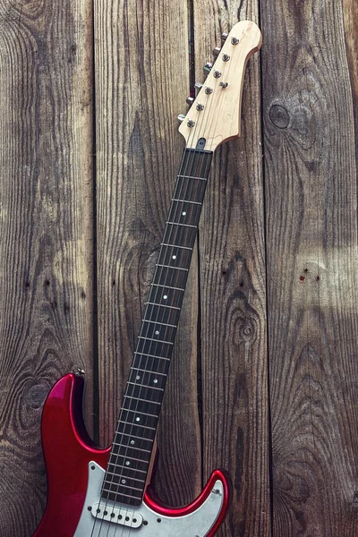 Red electric guitar on grunge wooden planks background. Place fo