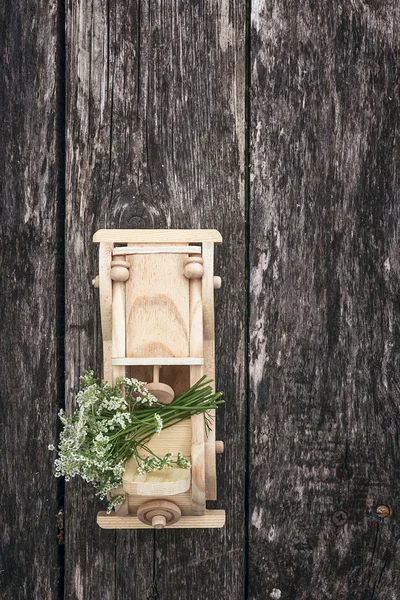 Wooden toy car with bouquet of wild flowers on a background of o