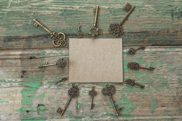 Background with blank card and antique keys on old painted woode