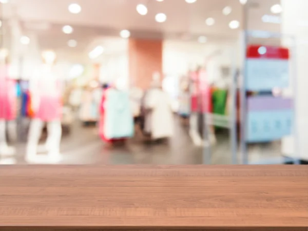 Wooden empty table in front of blurred dress store