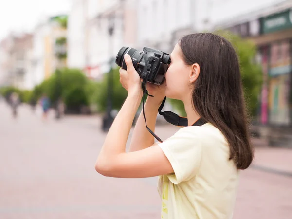 Cheerful young woman watching shots on dslr camera