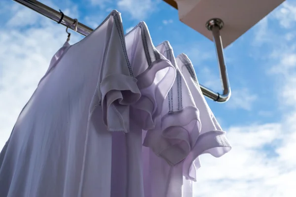 White T-shirts on clothesline against blue sky.