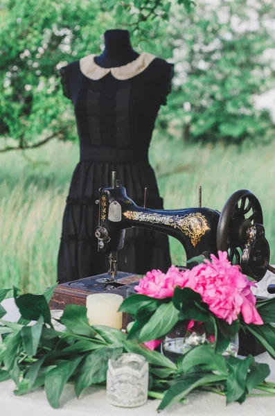 Sewing machine, mannequin in dress and pink flowers