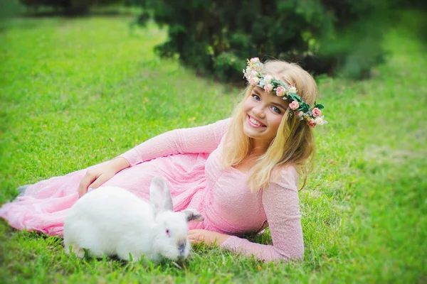 Alice in Wonderland, fairy rabbit play with a rabbit, white rabbit, wreath, girl, blond, cute girl, grass, lying, smile, sincere smile, playing with rabbit, rabbit train, games in nature, nature, wreath of roses, roses, dress, pink, lace, iron rabbit