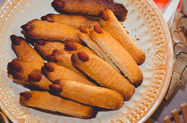 Decoration on halloween, holiday, halloween, halloween witch, witch's fingers, terrible biscuits, cookies for Halloween, candy, almonds, nails, fingers, witches fingers vvide biscuits, sweet biscuits, nut, plate, pastry on a plate