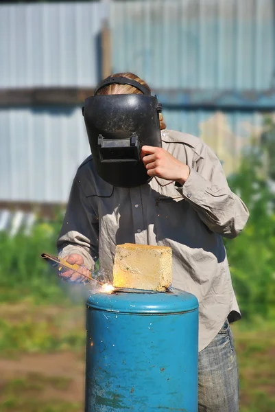 Welder in black mask works outdoor