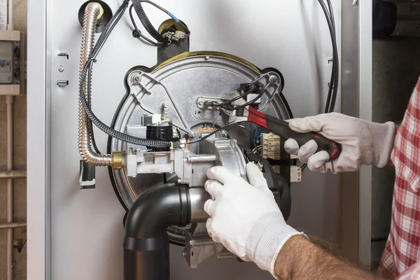 Plumber repairing a condensing boiler in the boiler room