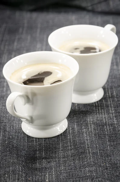Two cups of coffee on denim background