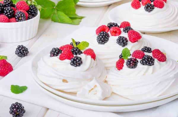 Meringue cakes Pavlova with whipped cream and fresh berries