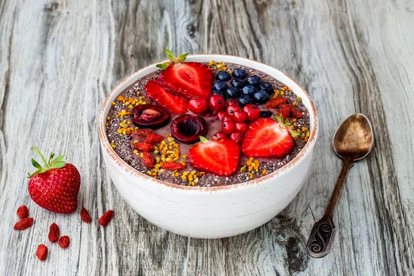 Acai breakfast superfoods smoothies bowl with chia seeds, bee pollen, goji berry toppings and peanut butter. Overhead, top view.