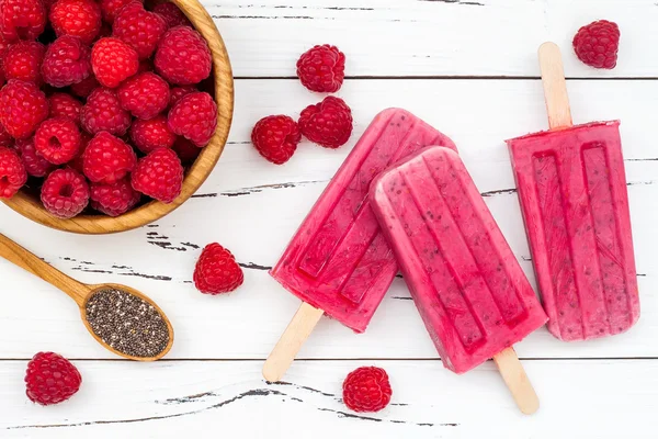 Homemade vegan raspberry coconut milk popsicles - ice pops - paletas with chia seeds on rustic white wooden background