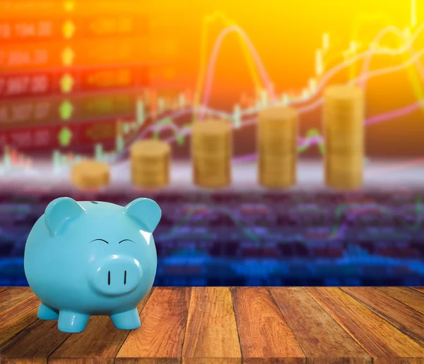 Blue pig bank on wood background with blur stock market backgrou