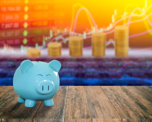 Blue pig bank on wood background with blur stock market backgrou