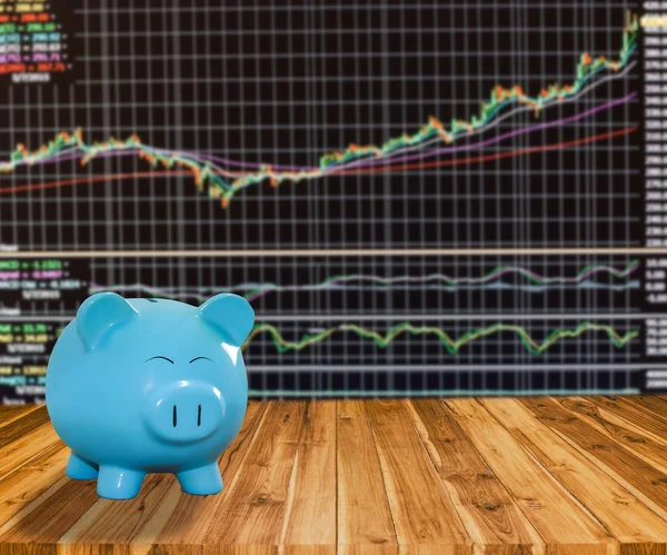 Blue pig bank on wood background with blur stock market backgrou