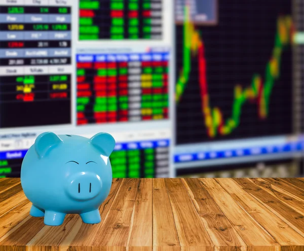 Blue pig bank on wood background with blur stock market backgrou