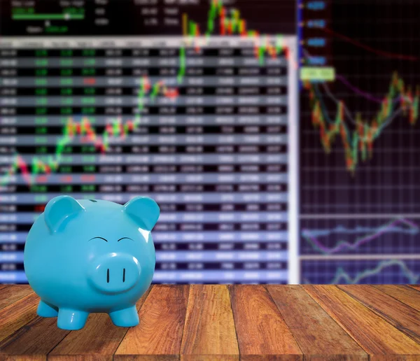 Blue pig bank on wood background with blur stock market backgrou