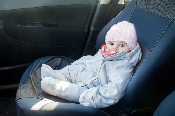 Newborn in car sitting on front seat dressed for winter
