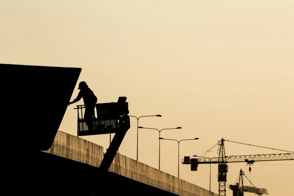 Silhouette of construction worker on scaffolding in the construc