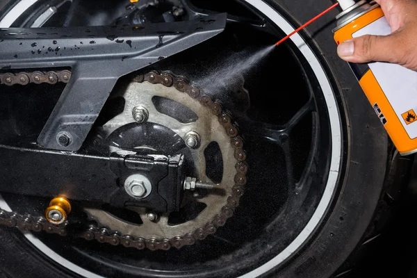 Cleaning and oiling a motorcycle chain and gear with oil Spray.