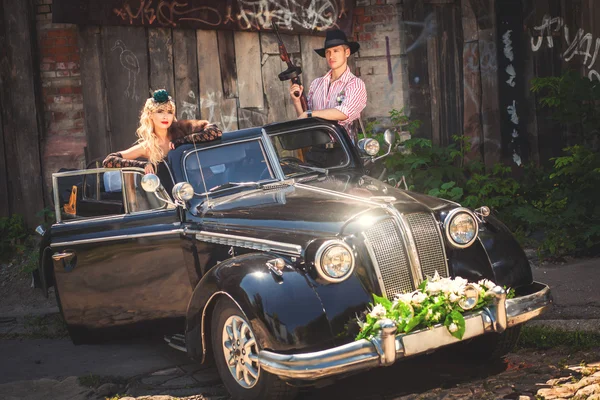 Model and man with gun in old car