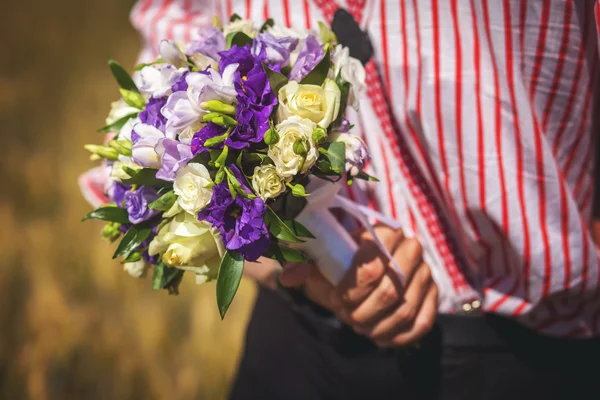 Man with bouquet on wheat field