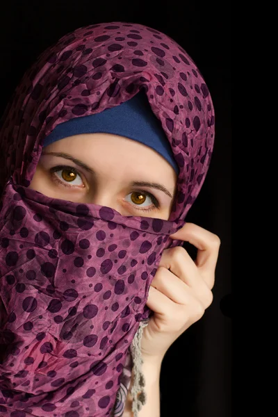 Young muslim women in niqab with brown eyes, on a black background